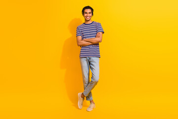 Fototapeta na wymiar Full length photo of good mood man with piercing cornrows wear stylish t-shirt standing arms crossed isolated on yellow color background