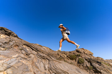 Fototapeta premium tourist girl with a backpack on her back climbs the mountain in summer