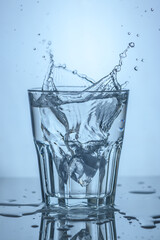 a glass of clean water into which an ice cube was thrown, water splashes 2