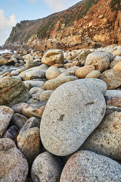 Granite boulders strewn across the shore at Porth Nanven, at the end of Cot Valley, near St. Just, Atlantic coast of the far west of Cornwall, England, United Kingdom