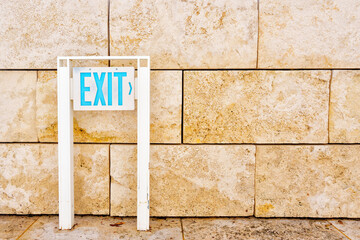 Exit Sign Placed in Front of a Stone Wall
