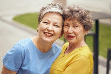 Obraz premium Close up of happy middle age women hug and look at camera on city street. Female friendship