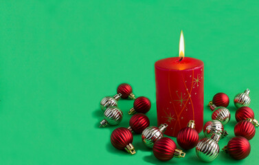 Christmas red burning candle and colored beans on the green background. Copy space.