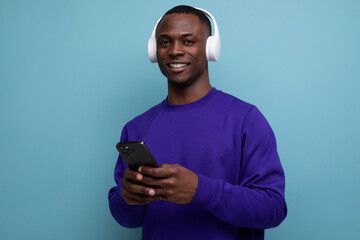 a handsome young man living in America with wireless headphones holding a smartphone