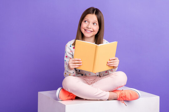 Photo of shiny dreamy little girl dressed dotted pullover preparing homework looking empty space isolated purple color background
