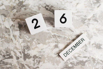 Flatlay, wooden calendar with date December 26 on white textured background.