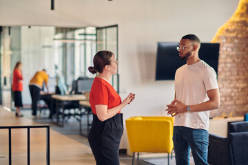 Young business colleagues, including an African American businessman, engage in a conversation about business issues in the hallway of a modern startup coworking center, exemplifying dynamic problem
