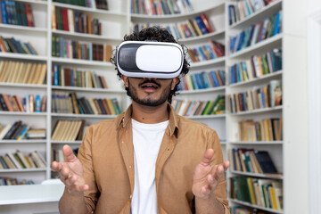 Young student close-up inside university academic library studying, man uses VR virtual reality glasses to watch course videos and online material.