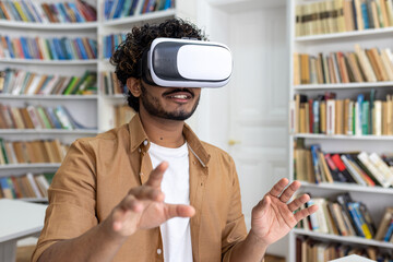 Young student close-up inside university academic library studying, man uses VR virtual reality...