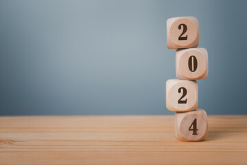 Wooden Cube turns from 2023 to 2024 on wooden table, Happy new 2024 year, countdown and New Year...