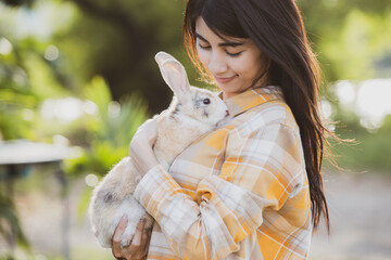 relationships of cheerful rabbit and happy young human girl, Asian woman holding and carrying cute rabbit with tenderness and love. Friendship with cute easter bunny. Happy of Easter's Day