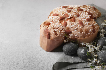 Delicious Italian Easter dove cake (Colomba di Pasqua), flowers and decorated eggs on grey table. Space for text