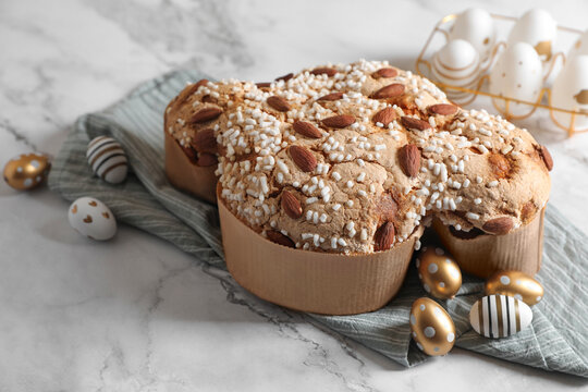 Delicious Italian Easter dove cake (Colomba di Pasqua) and decorated eggs on white marble table