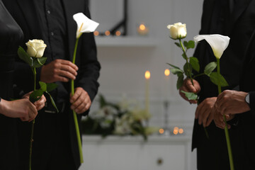 People with flowers indoors, closeup. Funeral ceremony
