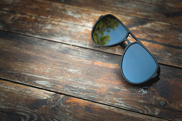 Fashionable male sunglasses on the old wooden table close up background with copy space. Top view.