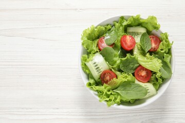 Delicious vegetable salad on white wooden table, top view. Space for text