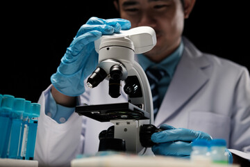male medical scientist examining specimen using microscope in modern laboratory.