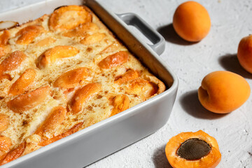 Clafoutis with apricot - summer pie in a baking dish and fresh apricots on the light table