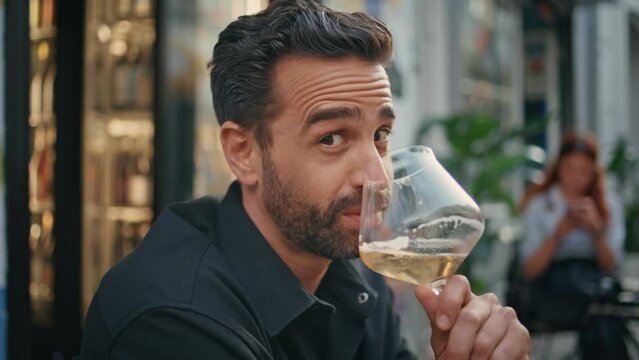 Portrait hot macho drinking wineglass at street bar. Smiling man looking camera
