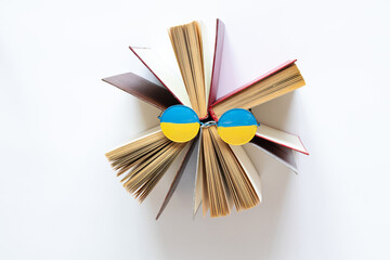 The flag of Ukraine is drawn on glasses that lie on open books on a white background, education