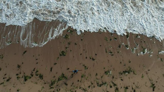 Luanda, Angola - August 17, 2023: drone view with the camera pointed down with filming the waves of the atlantic ocean on the edge of the beach