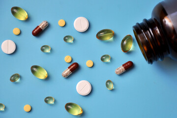 Pills, pills, vitamins scattered from a jar on a blue background