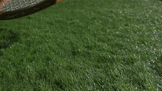 Super Slow Motion Shot of tennis ball and tennis racket at 1000 fps at natural grass during rain. Sport concept super slow motion shot on high speed camera 1000 fps. 