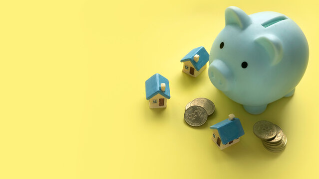 Concept of saving for house and property.Miniature house with piggy bank. Copy space.