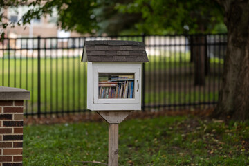 A Little Free Library in front of a fence