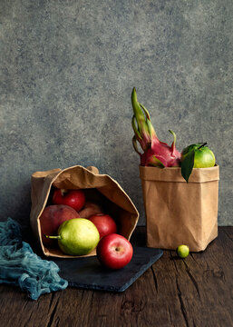 Fruits and vegetables in washable kraft paper bags on wooden table with copy space