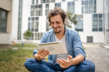 man sit in front of modern building use digital tablet watch movie