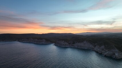 Fototapeta premium Beautiful aerial view of cliffs overlooking the ocean at sunset