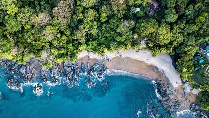 an aerial view of a sandy beach with blue water and evergreens