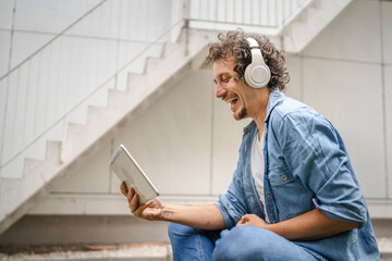 man sit in front of modern building use digital tablet watch movie