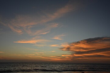 Naklejka na ściany i meble Beautiful golden sunset paints the sky over a serene blue ocean