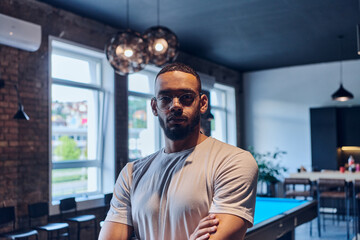 An African American businessman posing with crossed arms, exuding confidence and empowerment within the modern business setting of a startup coworking center.
