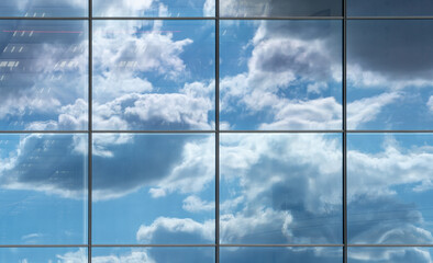 View upwards of a glass facade of a modern office building reflecting the clouds in the sky