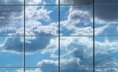 Fototapeta na wymiar View upwards of a glass facade of a modern office building reflecting the clouds in the sky