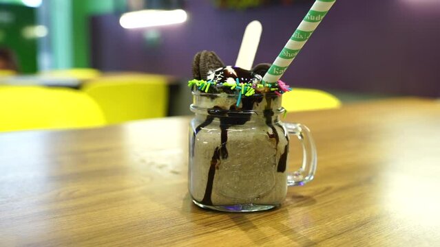 A refreshing and creamy milkshake with vanilla ice cream, chocolate, Oreo cookies in Indian caf&eacute; closeup scene with blur background stock footage.