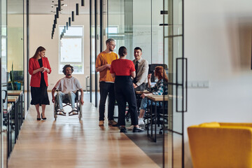 Fototapeta premium A group of young business people in a modern glass-walled office captures the essence of diversity and collaboration, while two colleagues, including an African American businessman in a wheelchair