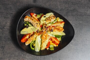 Closeup of a salad topped with chicken nuggets