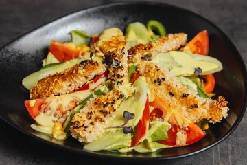 Closeup of a salad topped with chicken nuggets