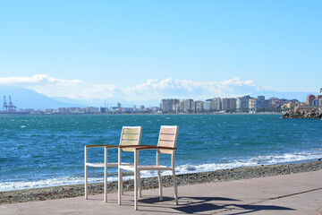 Two chairs on the beach. Seashore overlooking the sea and the city in the distance. Malaga, Spain. Two chairs without people.