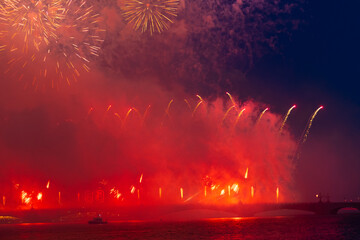 Beautiful red firework explodes in night city sky above bridge. Pyrotechnic display. Copy space for your text. Holiday celebration theme.	
