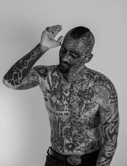Grayscale of a Caucasian man with whole body covered in traditional tattoos on the white background