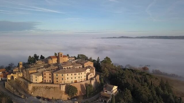 Aerial view of the medieval Village of Piticchio with old buildings and trees covered by clouds
