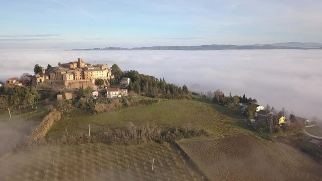 Aerial view of medieval village of Piticchio with old buildings and trees covered by clouds