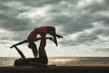 Fit young couple doing acro yoga for healthy lifestyle on tropical coast