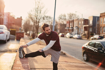 Young caucasian man stretching before jogging and exercising on a sidewalk in St Louis USA