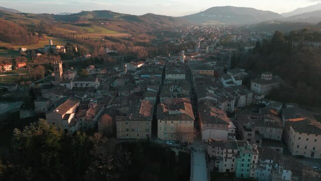 Aerial footage flyover traditional houses with trees in an Italian village at sunset